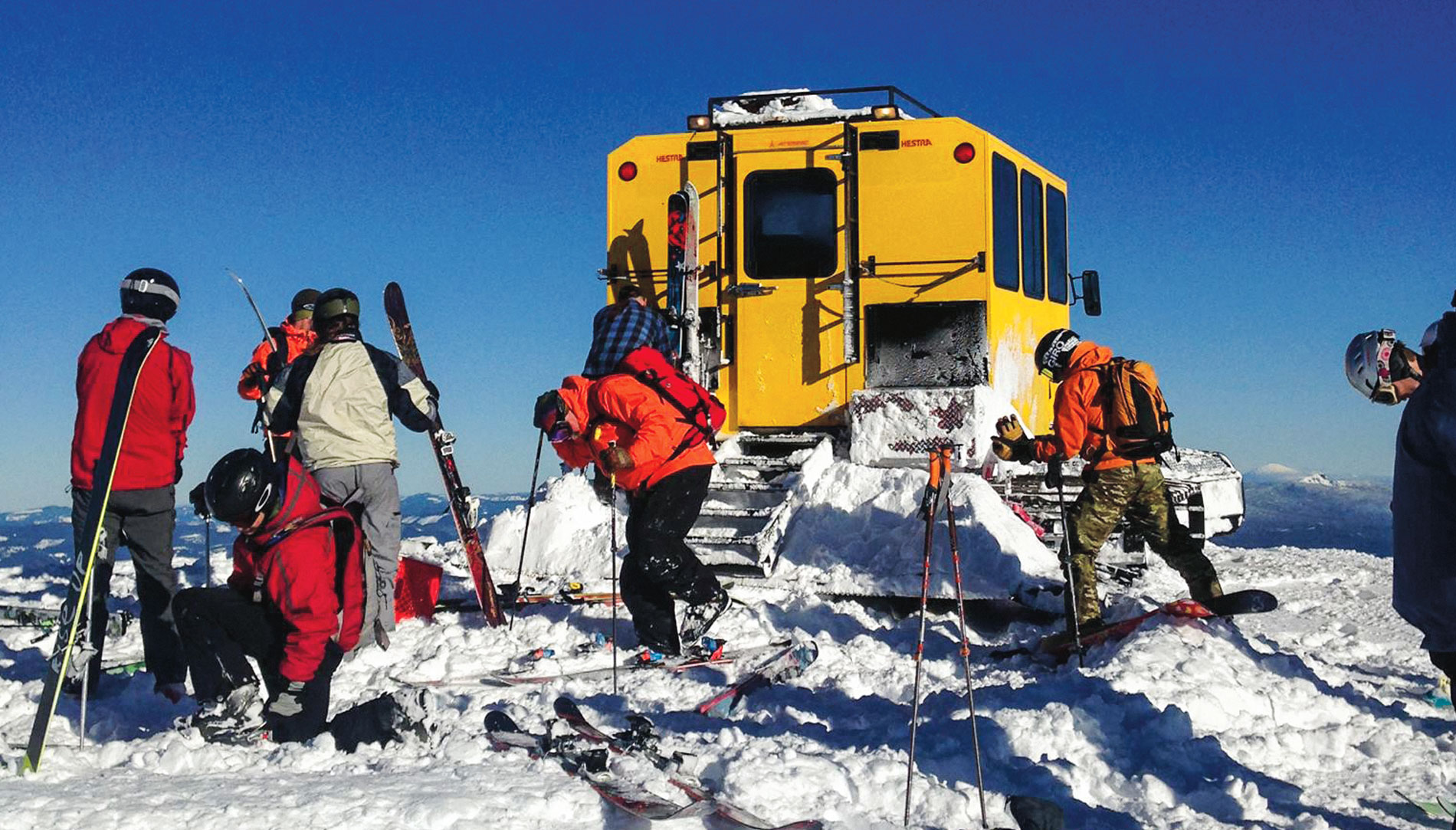 Skiers and a snowcat mountain climbing vehicle at Mount Bailey in Oregon