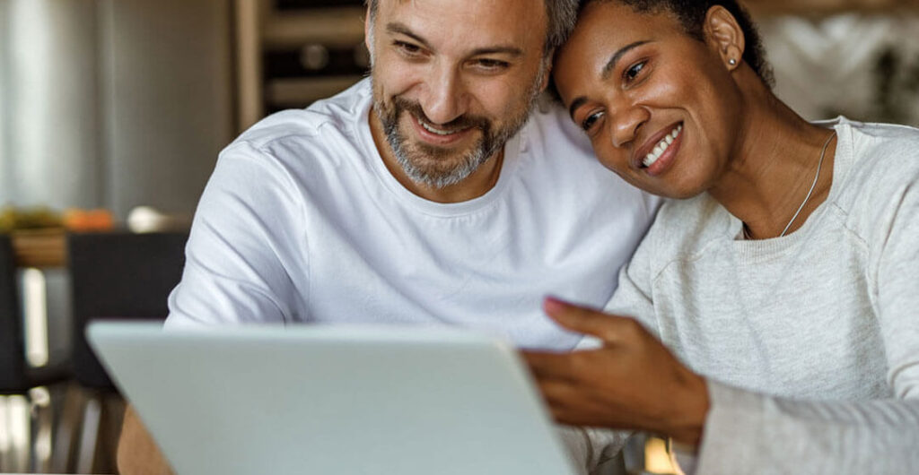 A couple looks over a laptop while researching home insurance options. 