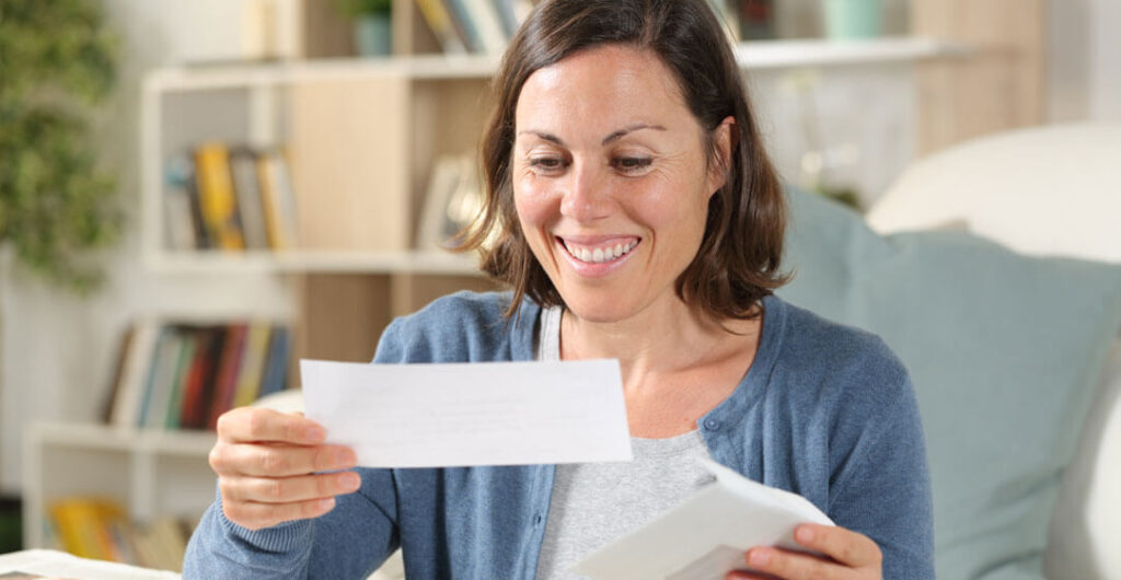 A woman looks at a check from an insurance payout on home insurance. 