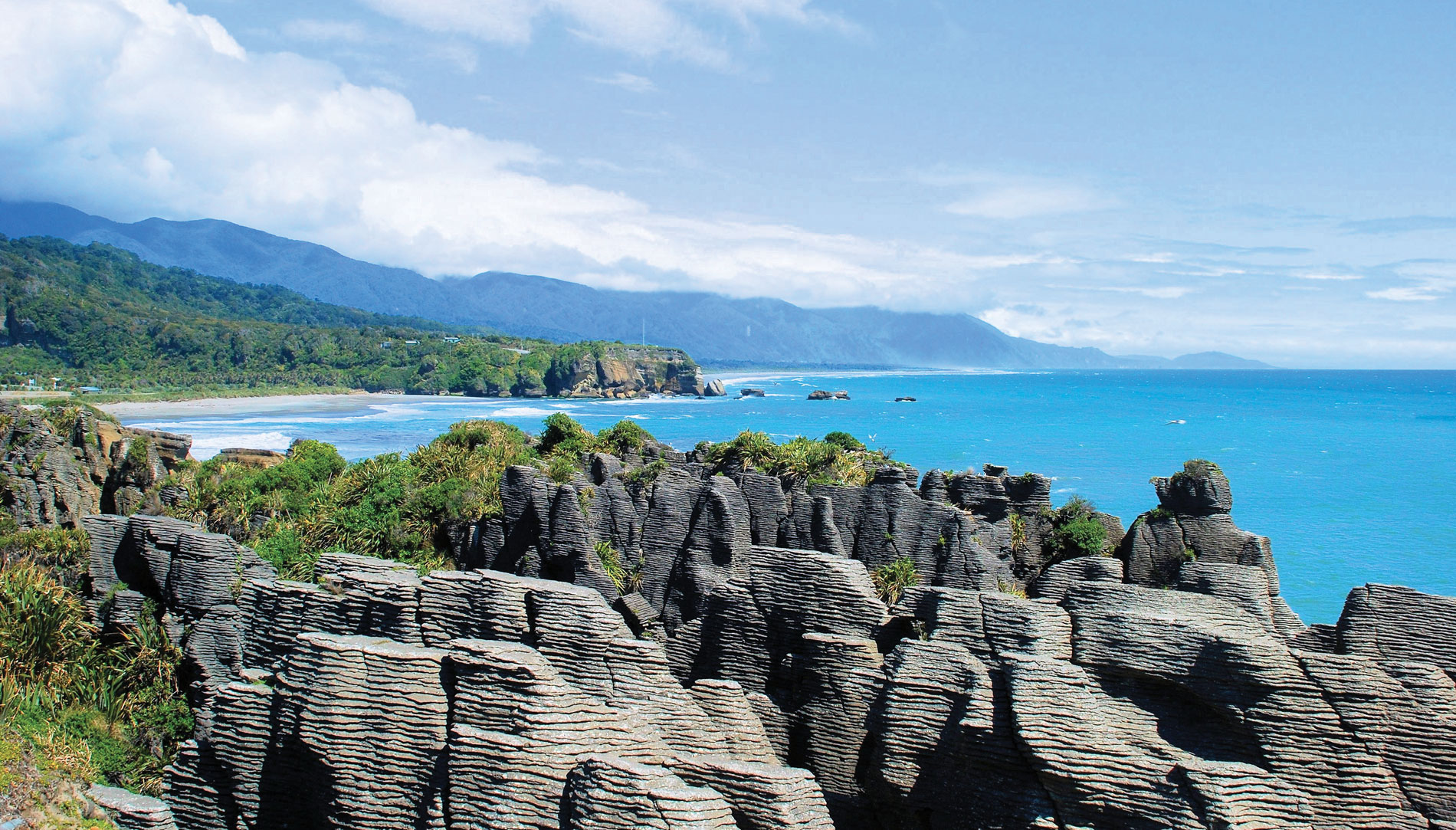 The layered Pancake Rocks at Punakaiki in New Zealand with blue ocean water in the distance