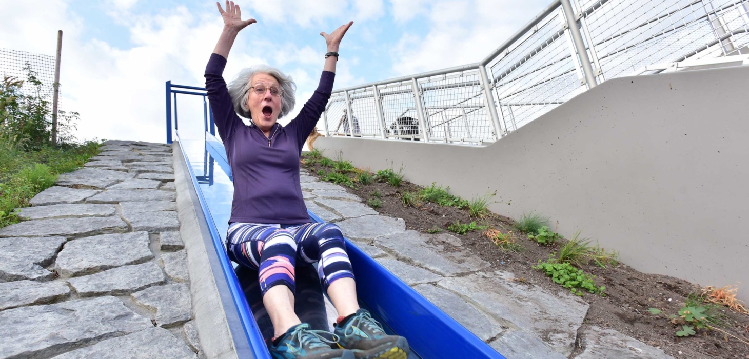 A woman rides a slide from the Wilson Way bridge down to Dune Peninsula at Point Defiance Park in Tacoma