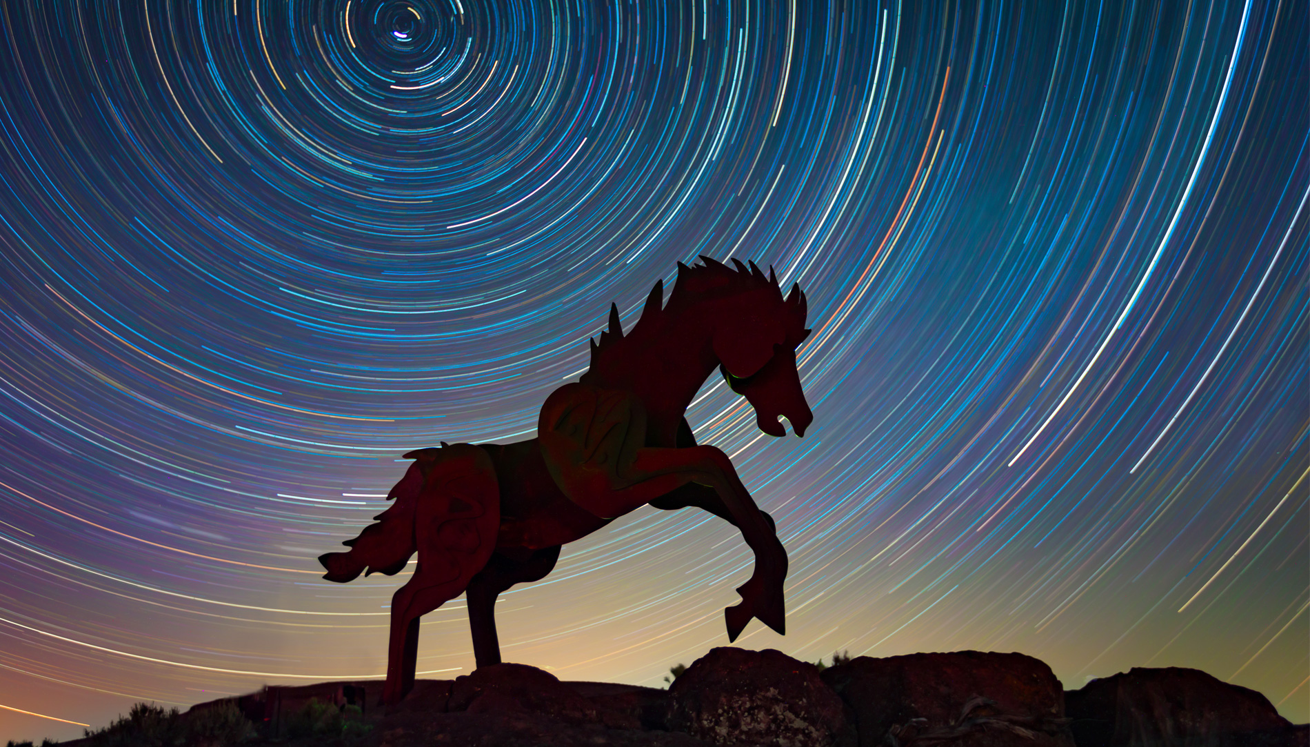 A long-exposure photo captures star trails — the apparent motion of stars as the Earth rotates — over David Govedare’s “Grandfather Cuts Loose the Ponies” sculpture near Vantage, Washington.