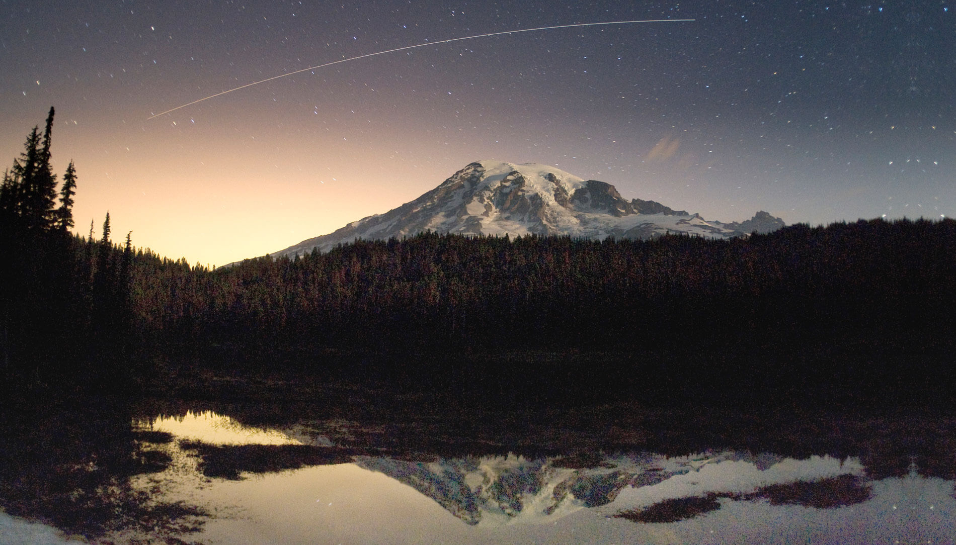 The International Space Station passes over Mount Rainier in this multiple-second photo exposure