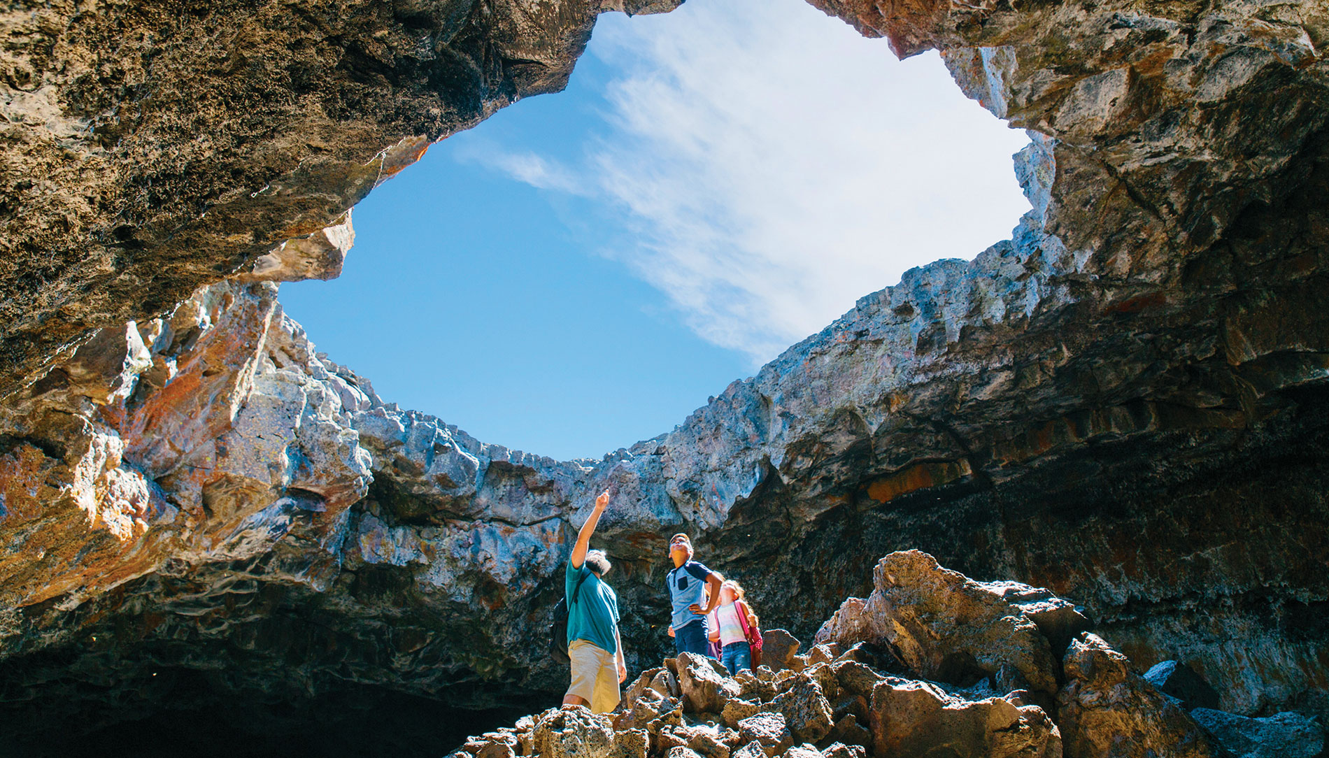 A family explores a cave at Craters of the Moon National Monument and Preserve