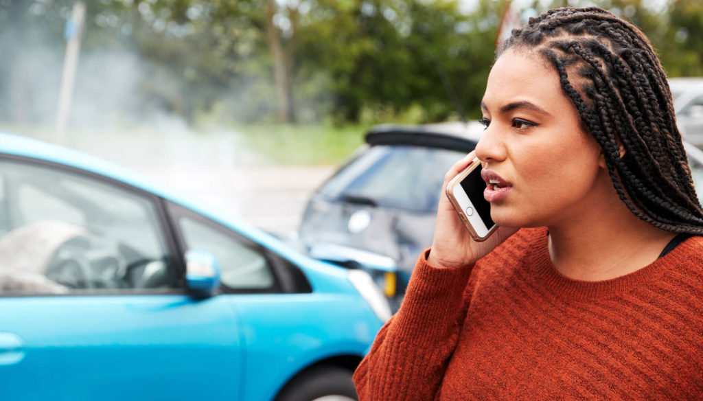 Woman on the phone with a car crash in the background