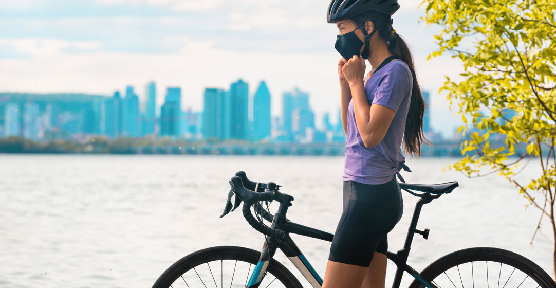 Woman in a helmet and mask riding a bike
