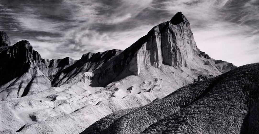 Black and white photo of a craggy mountain peak by Ansel Adams