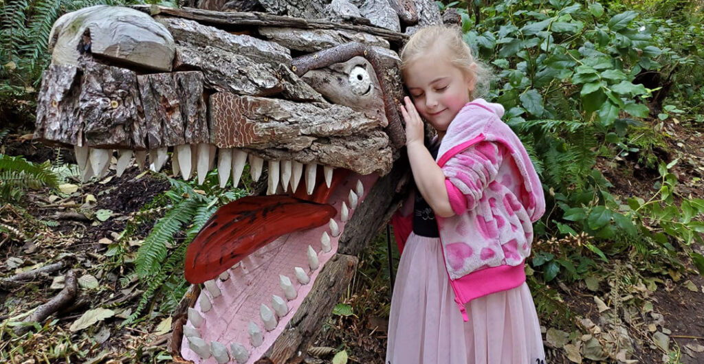 Girl stands next to T Rex carving on Whidbey Island