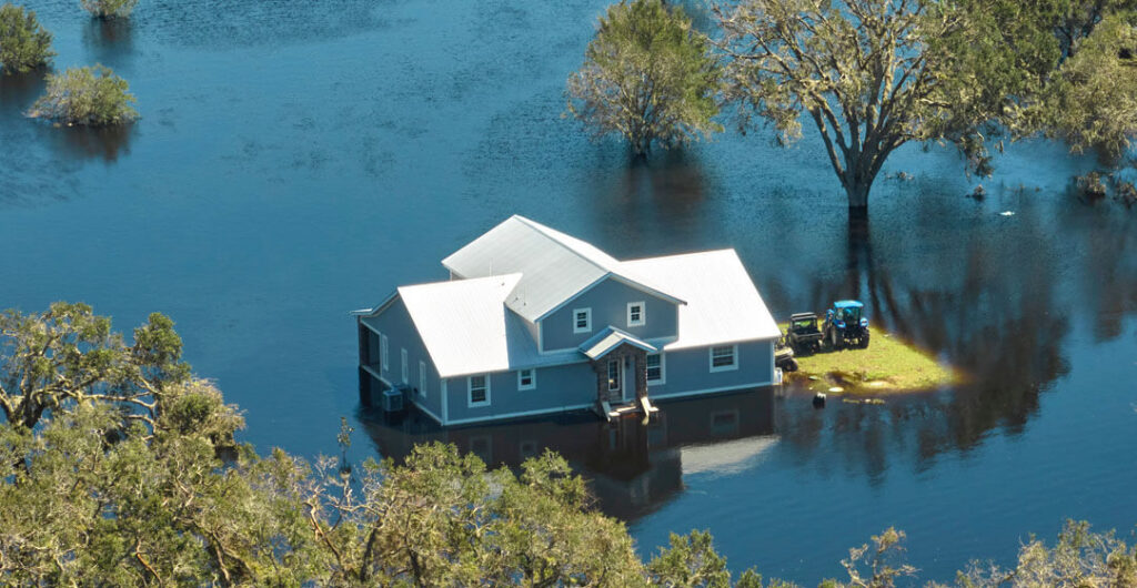 A real shot of a home surrounded by water in a flood. 