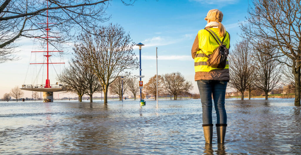 A woman is standing in a flooded street. 