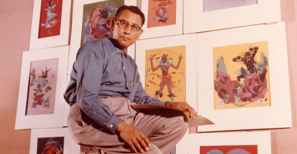 Oscar Howe seated in front of a selection of his paintings at South Dakota State University