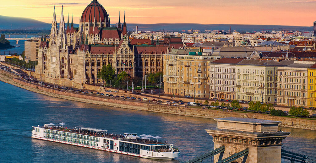What's new in cruising in 2023? New ships! A cruise ship cruises on the Danube past the Baroque buildings of Budapest. 