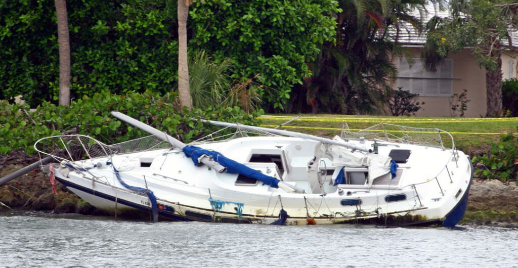 A beached boat that is disabled is pictured to illustrate the importance of boat insurance.