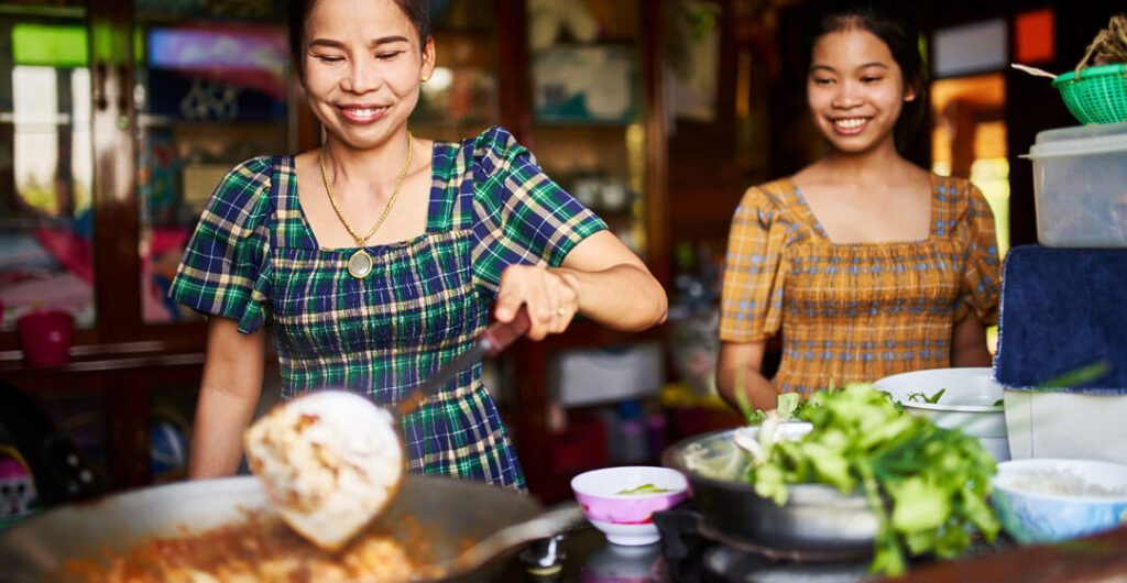Mother and daughter cook red curry together in Thailand. Learn how to cook Thai food on a foodie adventure tour with Club Adventures.