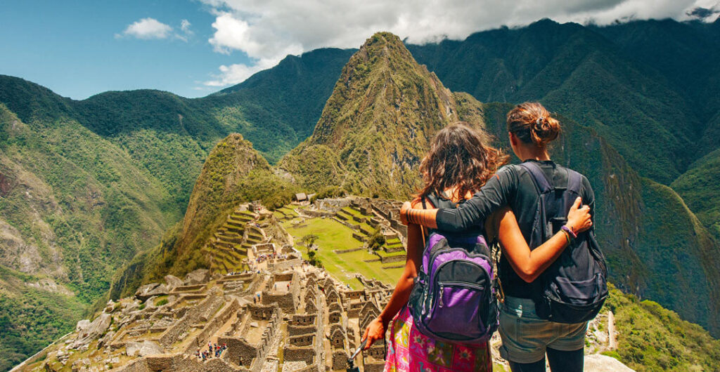 Two female hiker friends stand arm and arm while stand at the lost city of the Incas on Machu Picchu
