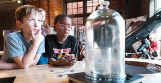 Two boys look at a glass cylinder at the Mobius Discovery Center
