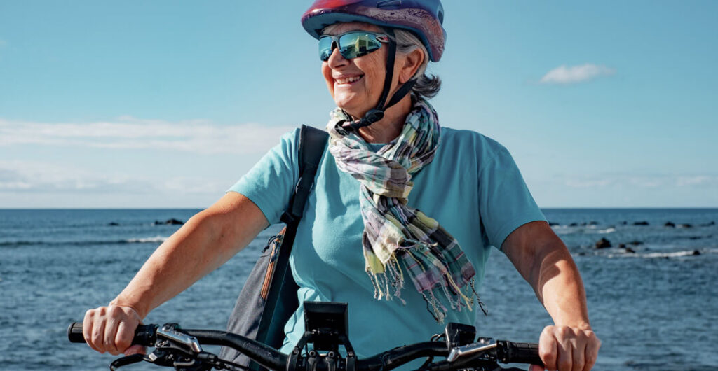 Woman on bicycle. Traveling with health issues can be enjoyable. A well-planned trip can provide comfort and ensure you meet your needs while traveling. 