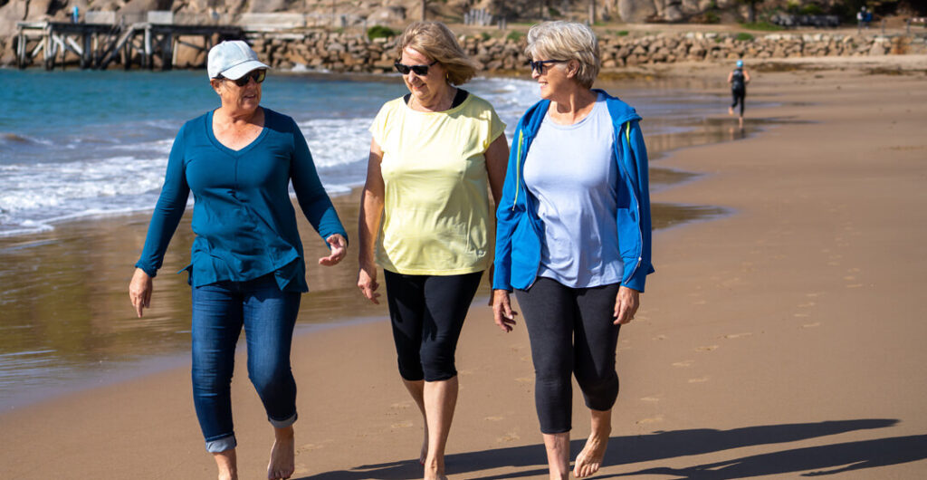 Women walking on the beach. Follow these tips to stay healthy while traveling abroad.