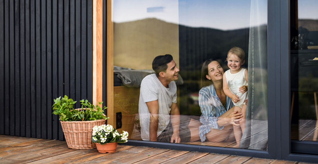 A young family in the window of a home, to illustrate the importance of homeowners insurance for new homebuyers