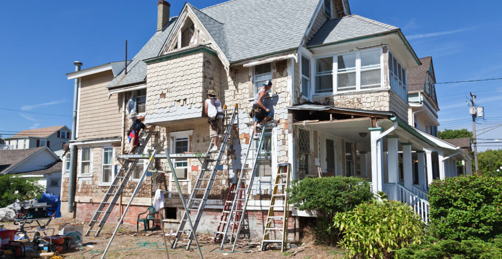 Workers fix up a home that has been damaged, to illustrate the importance of home insurance for new homebuyers
