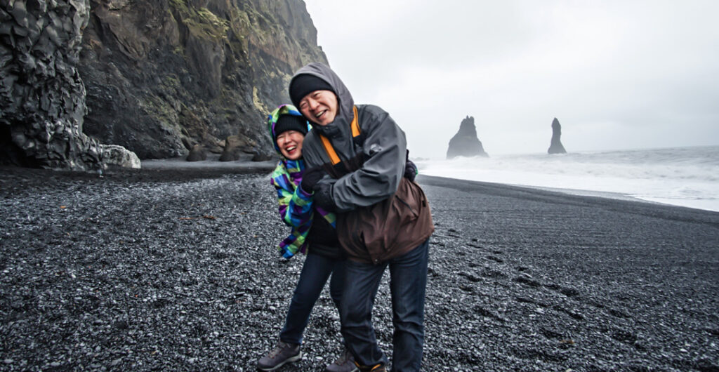Travelers on a black sand beach in Iceland.