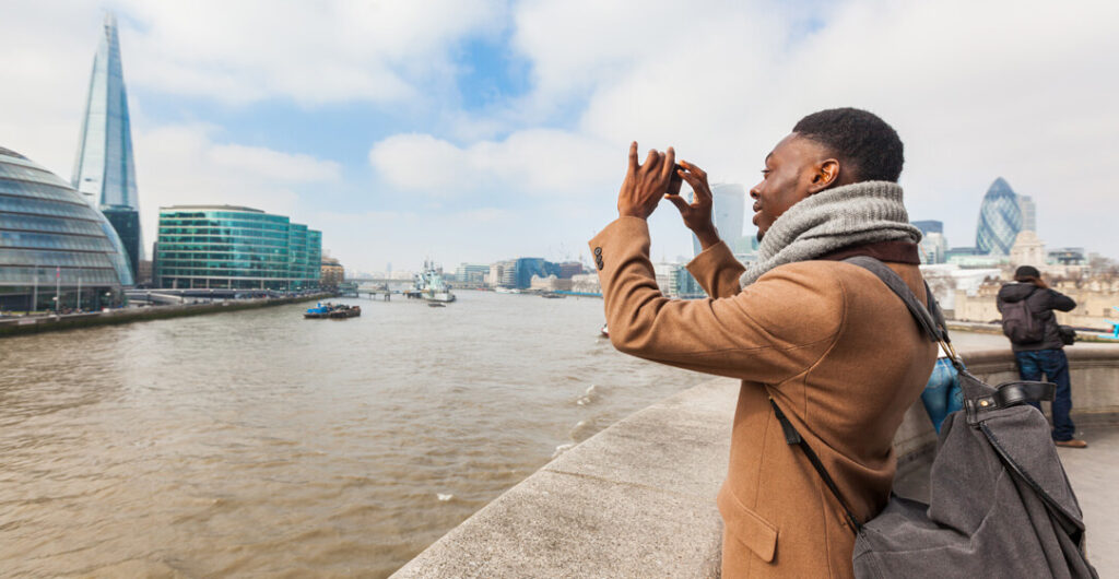 Man taking travel photo in London. Plan ahead to make traveling with health issues or conditions easier. AAA Washington travel agents are also available to help with all your travel needs.