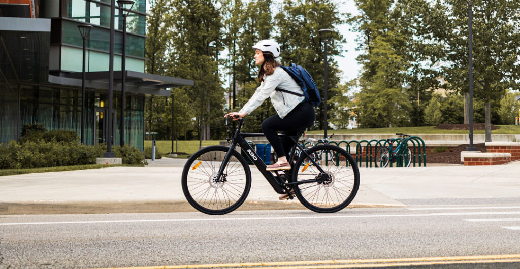 A woman keeps to the right of the road while riding an e-bike, to illustrate the rules of the road on an e-bike. 