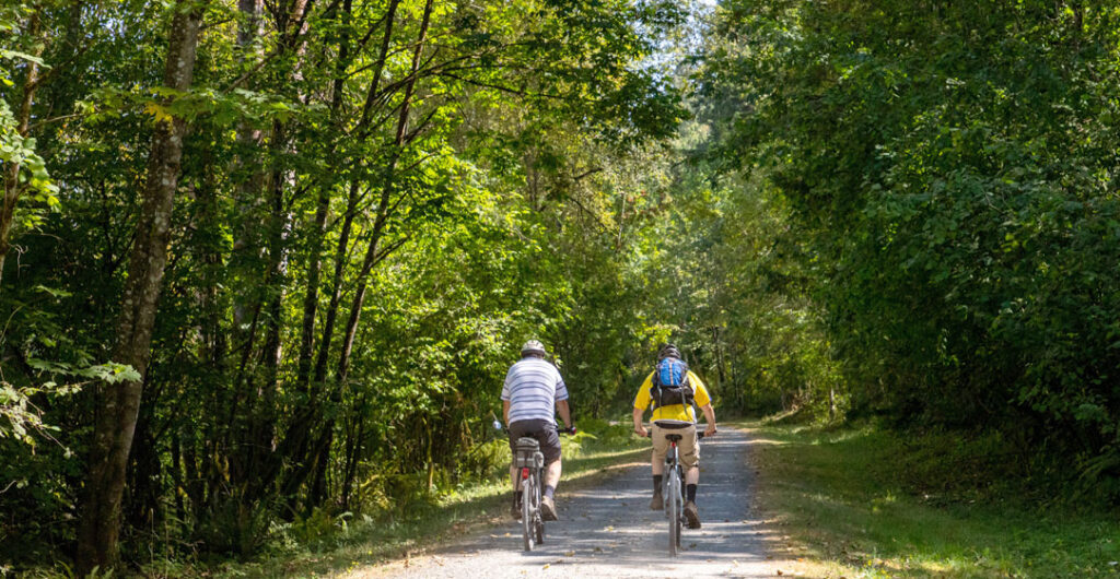Two cyclists ride along the Cedar River Trail in Washington state, to illustrate good trails for e-bikes. 