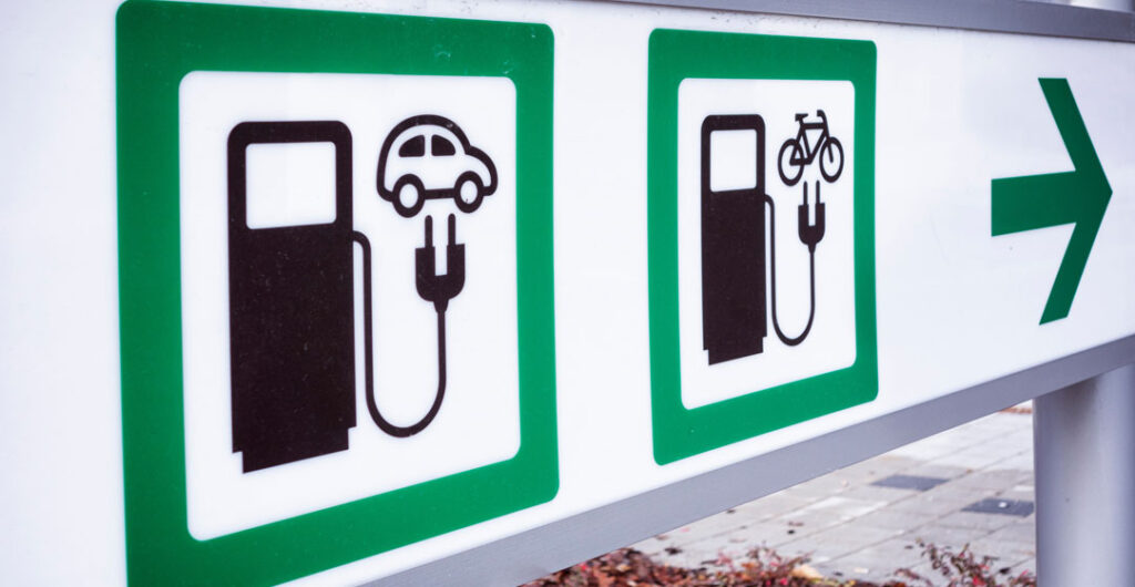 A sign that points to a charging station both for electric cars and for e-bikes