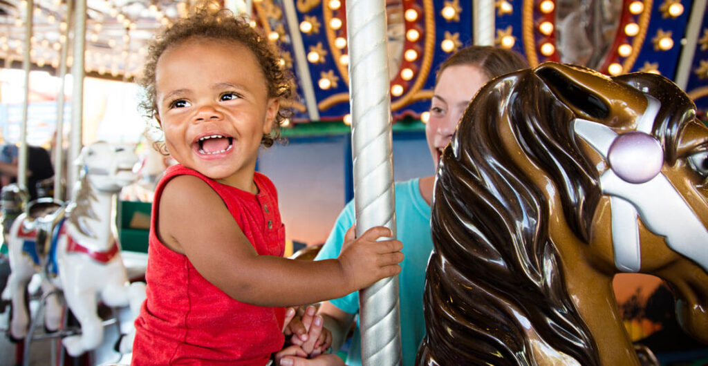 A toddler rides a merry go round, to illustrate the savings that you can get from AAA Tickets. Access to AAA Tickets is included in your AAA Washington membership, and offers up to a 30% discount on admission to major theme parks around the country. 