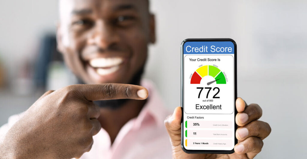 A man holds up a cell phone with a 772 credit score, to illustrate that good credit can save money on insurance for a new driver. 