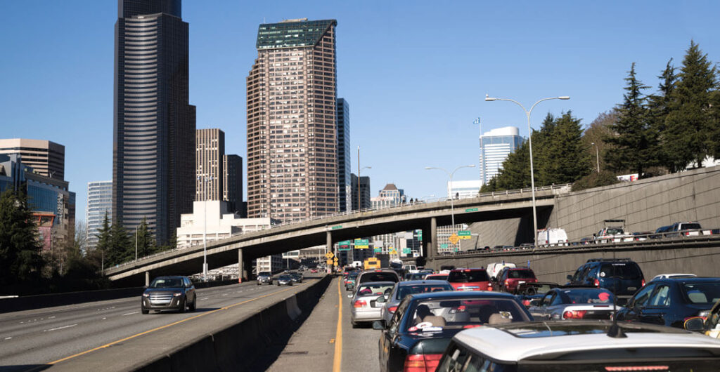Cars stuck on the freeway in dense city traffic to illustrate the need for a robust amount of auto insurance for new drivers. 